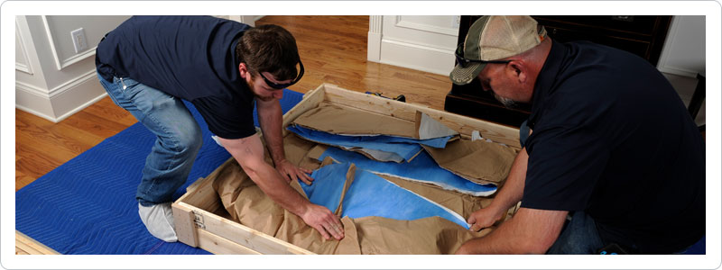 Two movers performing additional moving services by crating an item
