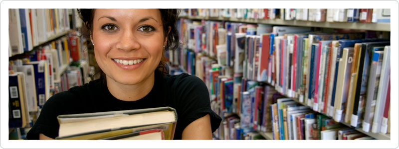 College student holding books in library researching moving tips