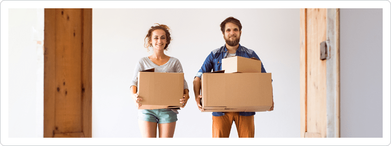 Millennial couple holding moving boxes