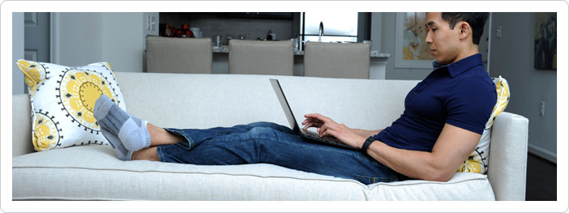 Young man sitting on couch weighing the costs of moving